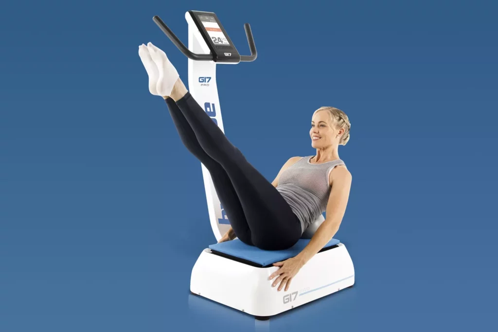 Top Vibration Plate Exercises: A Complete Guide To Safe Whole-Body Vibration Workouts 16 A woman performing a V-sit abdominal hold on a Hypervibe G17 Pro vibration plate with her legs extended upward.