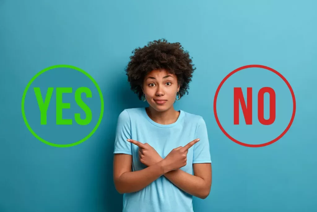 woman deciding yes or no whole body vibration Woman standing against a blue background, crossing her arms and pointing in opposite directions toward large YES and NO circles.