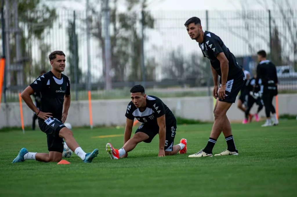 athletes pre game warm up flexibility stretching Soccer players performing dynamic hamstring and groin stretches on a grass field during a pre-game warm-up.