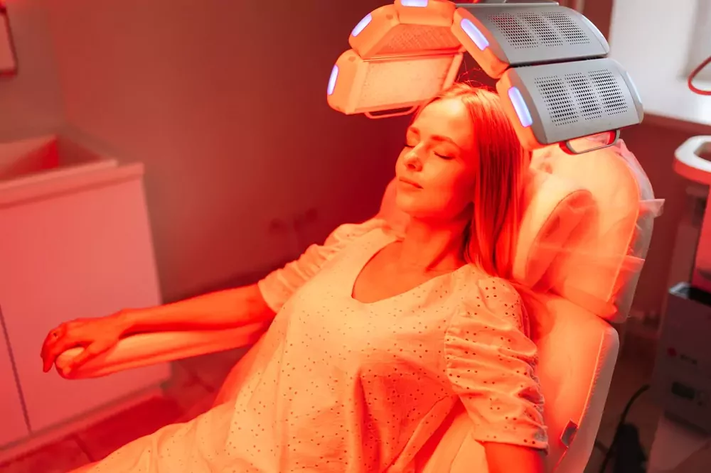 Woman lying on beds under red lights receiving red light therapy in a calm spaclinic setting