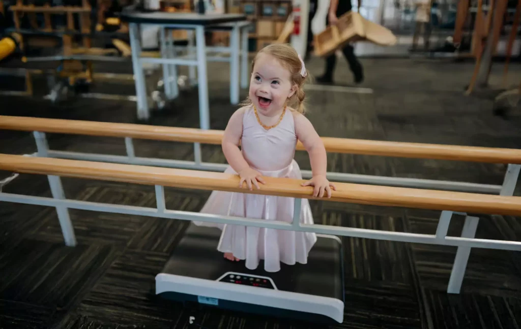 female child standing on a vibration plate and smiling