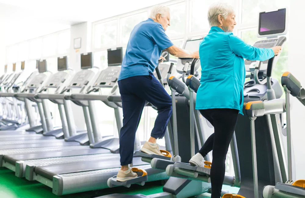 Elliptical Trainer Devices with two elderly persons training on them in a gym
