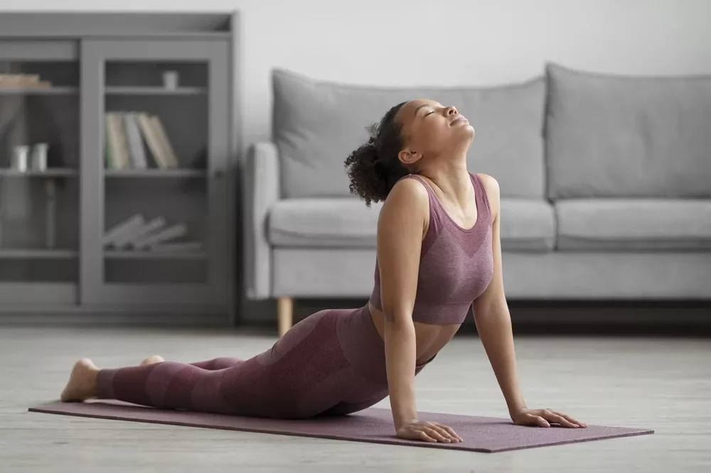 woman yoga upward dog posture stretch Woman on a yoga mat performing an upward-facing dog backbend in a living room.